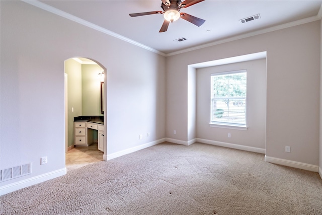 spare room featuring light carpet, arched walkways, a ceiling fan, and visible vents