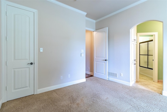 unfurnished bedroom with baseboards, ornamental molding, visible vents, arched walkways, and carpet floors