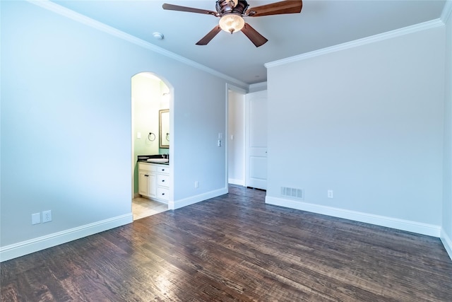 spare room with wood finished floors, ornamental molding, visible vents, ceiling fan, and arched walkways