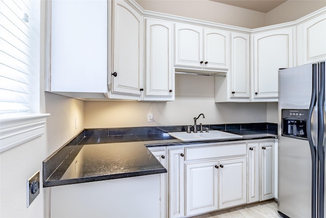 kitchen with stainless steel fridge, a sink, and white cabinets