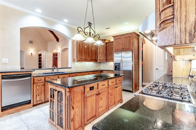 kitchen with a center island, a sink, crown molding, arched walkways, and appliances with stainless steel finishes