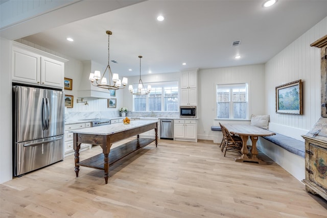 kitchen with white cabinets, stainless steel appliances, visible vents, and a notable chandelier