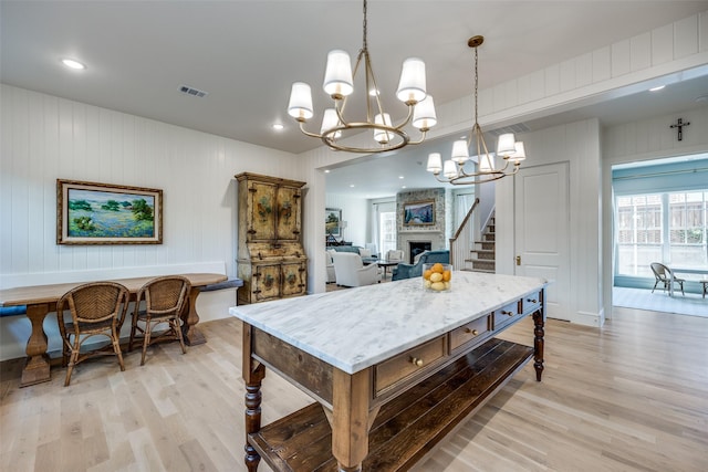 dining room featuring light wood finished floors, visible vents, a large fireplace, and a notable chandelier