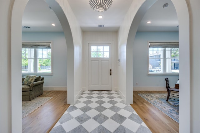 foyer with baseboards, light wood-type flooring, visible vents, and recessed lighting