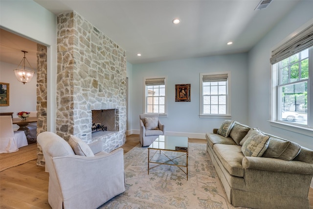 living room featuring visible vents, wood finished floors, a fireplace, and a healthy amount of sunlight