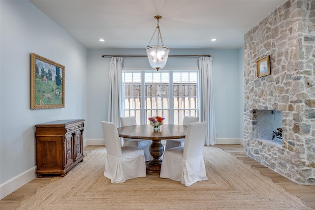 dining space featuring light wood-type flooring, baseboards, and a stone fireplace
