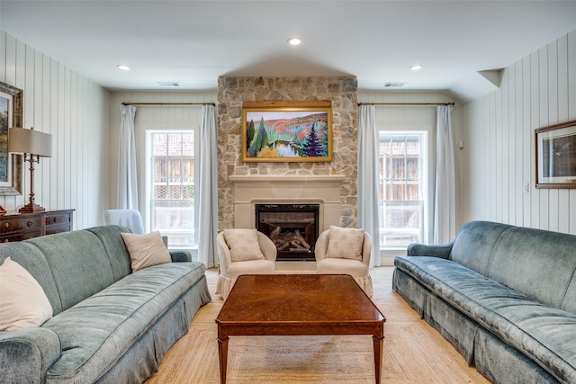 living area with a stone fireplace, plenty of natural light, and visible vents