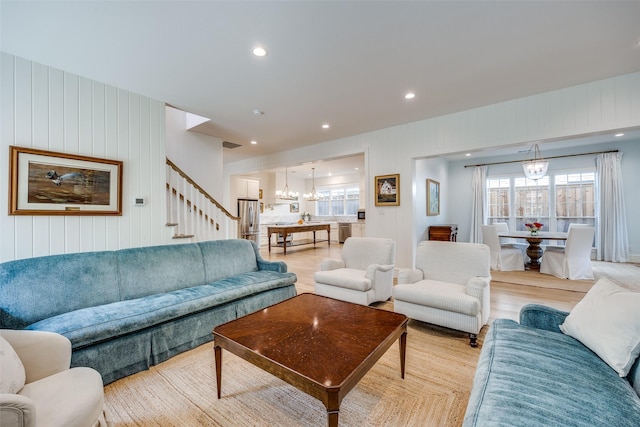 living area featuring light wood-style flooring, recessed lighting, an inviting chandelier, visible vents, and stairway