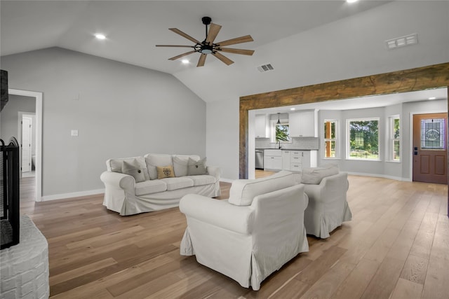 living area with lofted ceiling, baseboards, light wood finished floors, ceiling fan, and visible vents