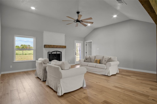 living room with visible vents, vaulted ceiling, ceiling fan, light wood finished floors, and a brick fireplace
