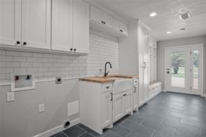 clothes washing area with a sink, cabinet space, washer hookup, dark tile patterned flooring, and hookup for an electric dryer