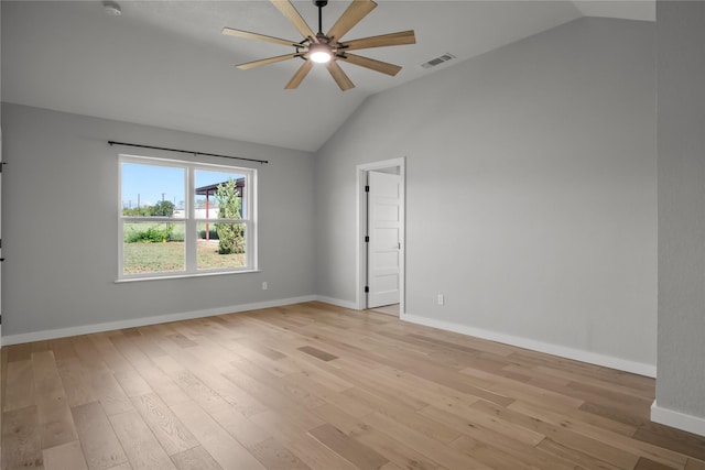 spare room featuring light wood-type flooring, visible vents, vaulted ceiling, a ceiling fan, and baseboards