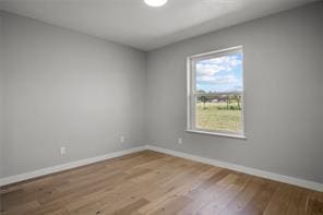 unfurnished room with baseboards and wood finished floors