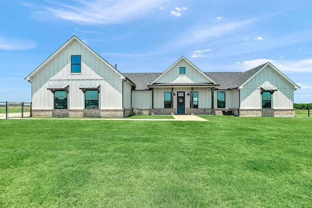 modern farmhouse style home with fence, a front yard, a shingled roof, and board and batten siding