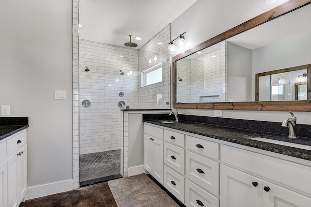 bathroom featuring a sink, a walk in shower, double vanity, and baseboards