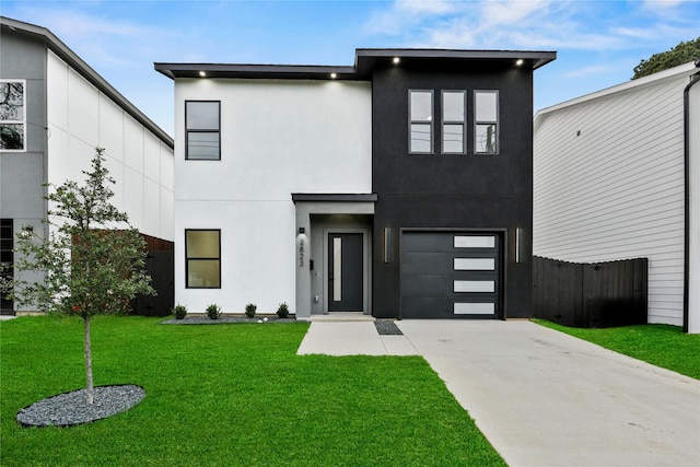 modern home with driveway, fence, an attached garage, stucco siding, and a front lawn