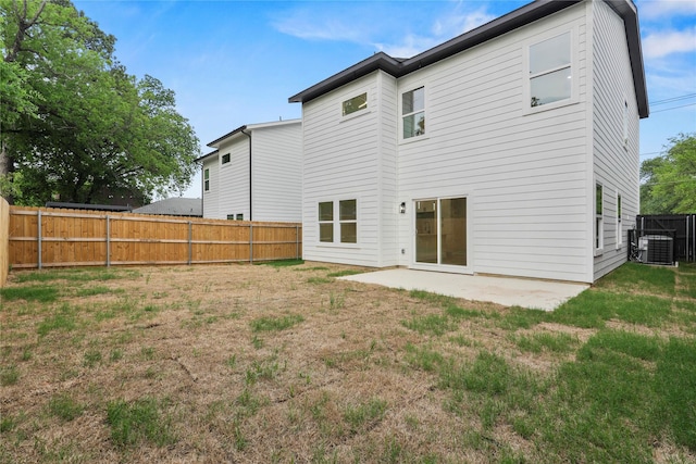 back of property with central AC, a patio area, a yard, and a fenced backyard