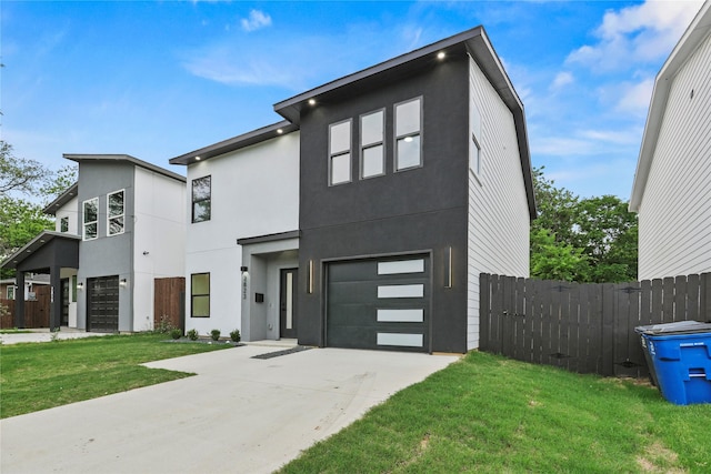 contemporary home featuring an attached garage, stucco siding, driveway, and fence