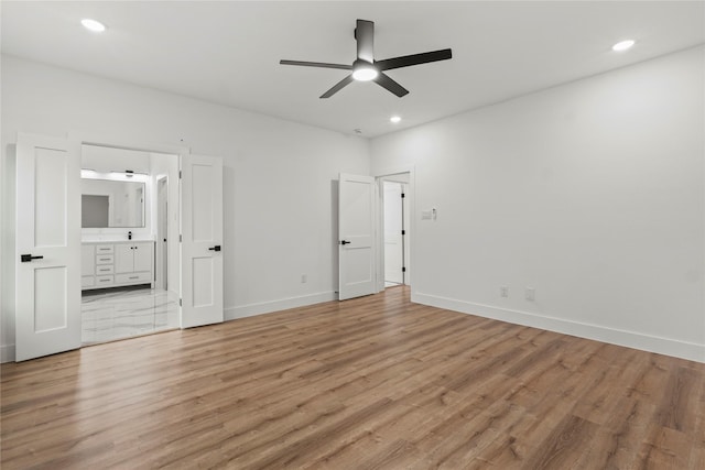 unfurnished bedroom featuring baseboards, ensuite bathroom, light wood-style flooring, and recessed lighting