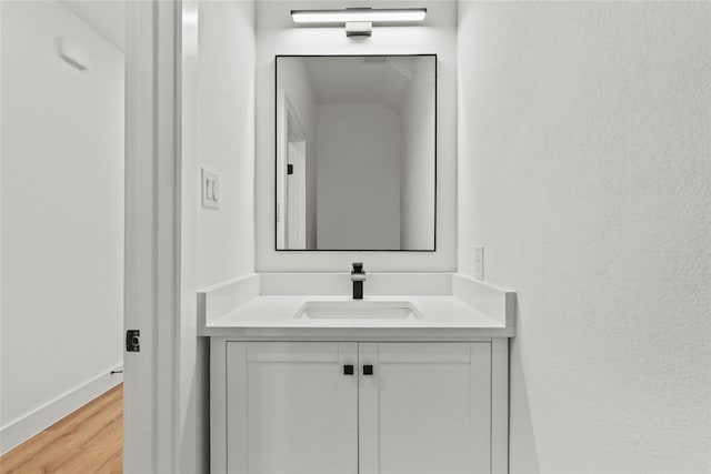 bathroom with baseboards, wood finished floors, and vanity