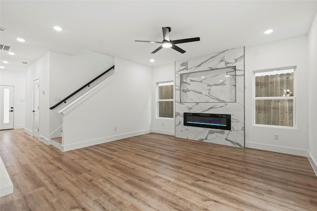 unfurnished living room with recessed lighting, baseboards, ceiling fan, a high end fireplace, and wood finished floors
