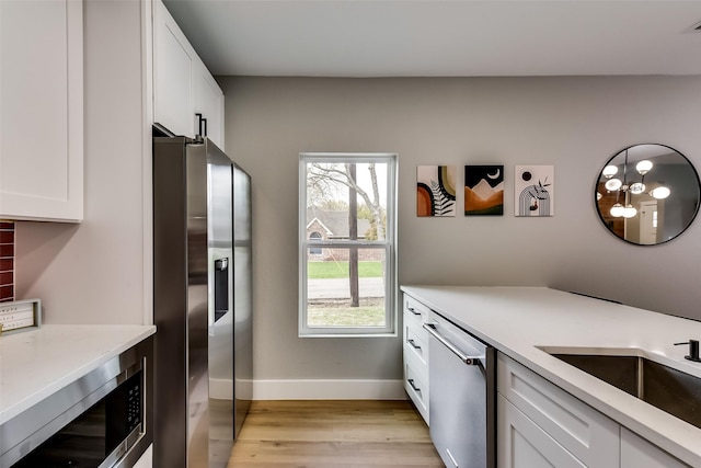 807 Florence St, Mckinney, TX 75069 - kitchen with a sink, stainless steel appliances, white cabinets, baseboards, and light wood-style floors