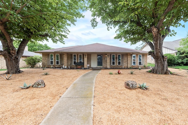 ranch-style home with covered porch, brick siding, and roof with shingles