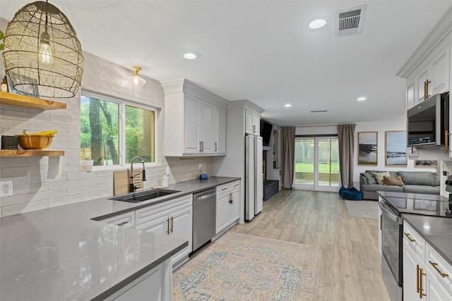 kitchen with stainless steel appliances, a sink, open shelves, tasteful backsplash, and white cabinets