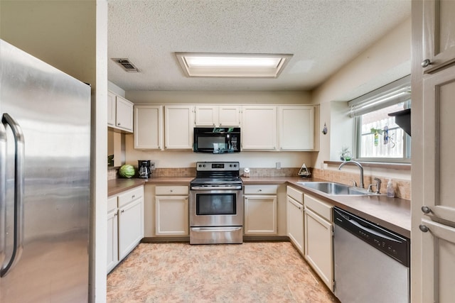 kitchen with stainless steel appliances, a sink, and a textured ceiling