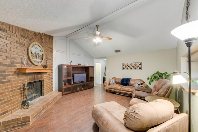living area with wood finished floors, ceiling fan, and a fireplace