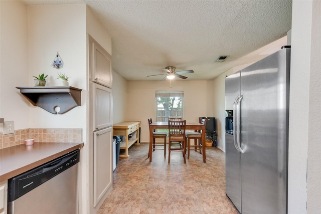 kitchen featuring appliances with stainless steel finishes, ceiling fan, a textured ceiling, light countertops, and tasteful backsplash