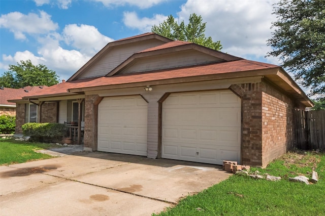 view of front of home with brick siding, a garage, driveway, and fence