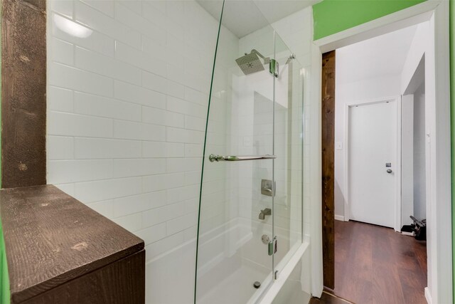bathroom featuring wood finished floors and enclosed tub / shower combo