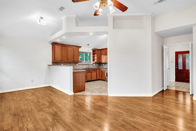 kitchen with visible vents, a peninsula, open shelves, high vaulted ceiling, and brown cabinets