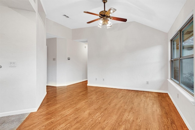 spare room with lofted ceiling, a ceiling fan, baseboards, light wood finished floors, and visible vents
