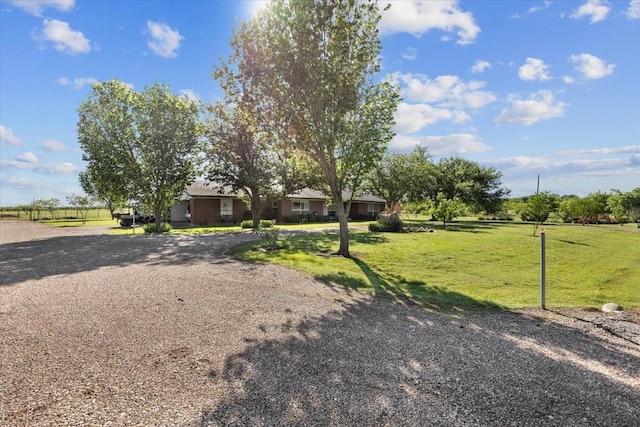view of front of home with a rural view and a front lawn