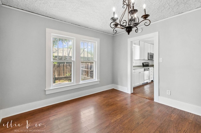741 Vine St, Abilene, TX 79602 - unfurnished dining area featuring a chandelier, crown molding, dark wood-style floors, baseboards, and an ornate ceiling
