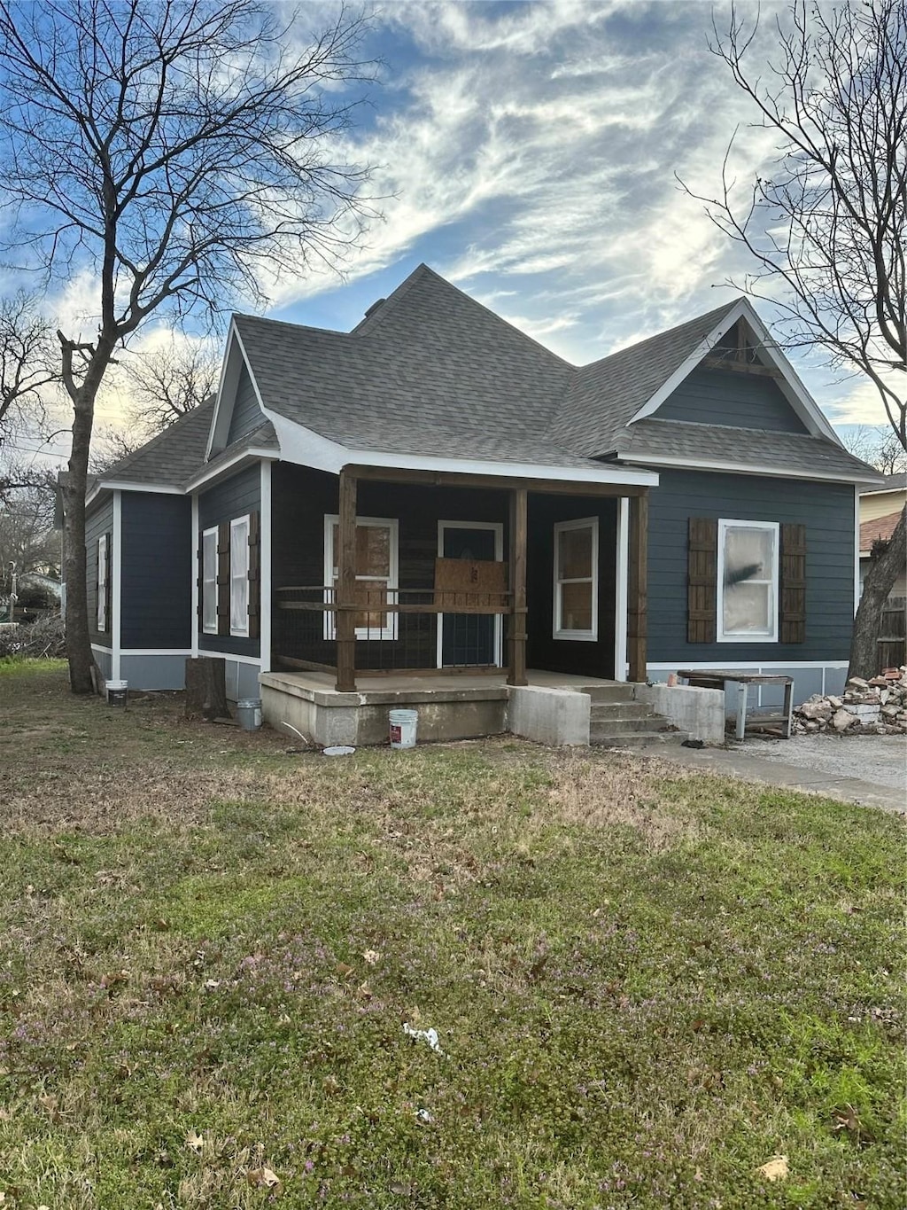 view of front of home with a porch, roof with shingles, and a front lawn