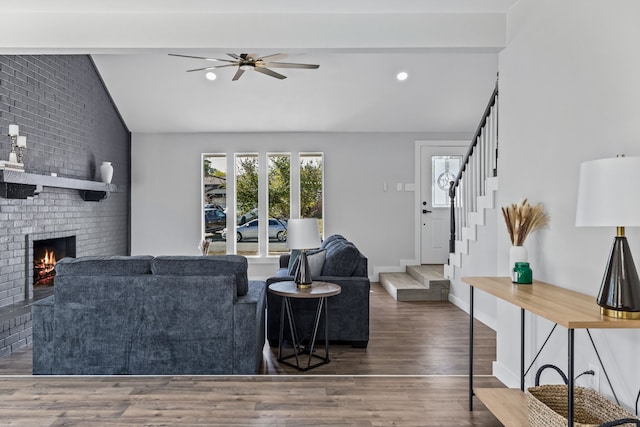 living area featuring wood finished floors, a fireplace, stairway, ceiling fan, and lofted ceiling