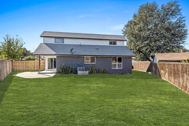 rear view of property featuring a patio area, roof with shingles, a lawn, and a fenced backyard