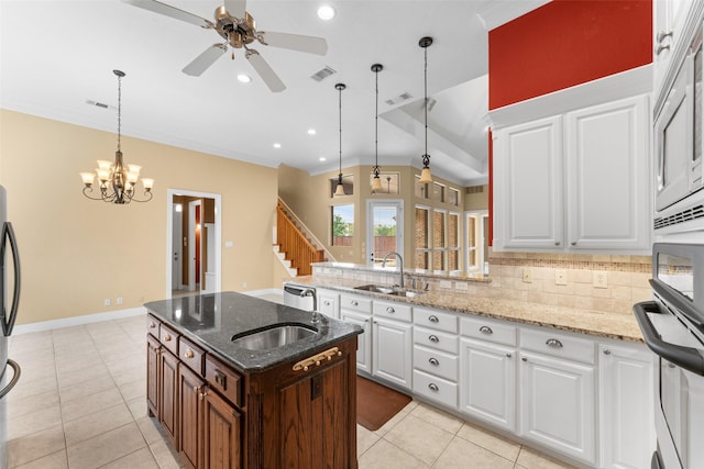 kitchen with decorative light fixtures, visible vents, a sink, ceiling fan with notable chandelier, and backsplash