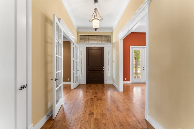 foyer entrance featuring french doors, wood finished floors, baseboards, and ornamental molding