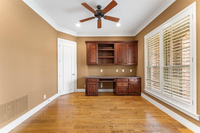 unfurnished office with a ceiling fan, light wood-type flooring, visible vents, baseboards, and ornamental molding
