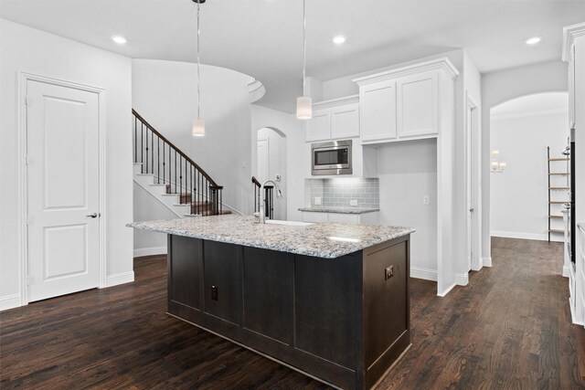 2507 Lavaca Dr, Euless, TX 76039 - kitchen with arched walkways, stainless steel microwave, a sink, white cabinetry, and recessed lighting
