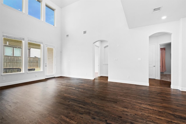 2507 Lavaca Dr, Euless, TX 76039 - unfurnished living room featuring plenty of natural light, a high ceiling, dark wood-type flooring, baseboards, and arched walkways