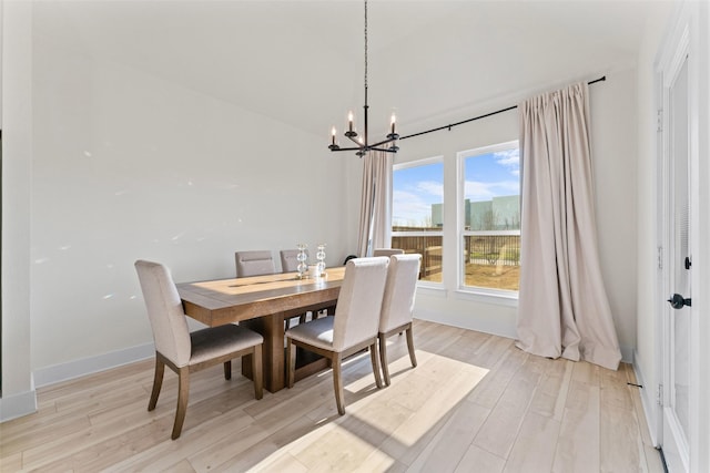 dining room with a notable chandelier, baseboards, and light wood-style floors