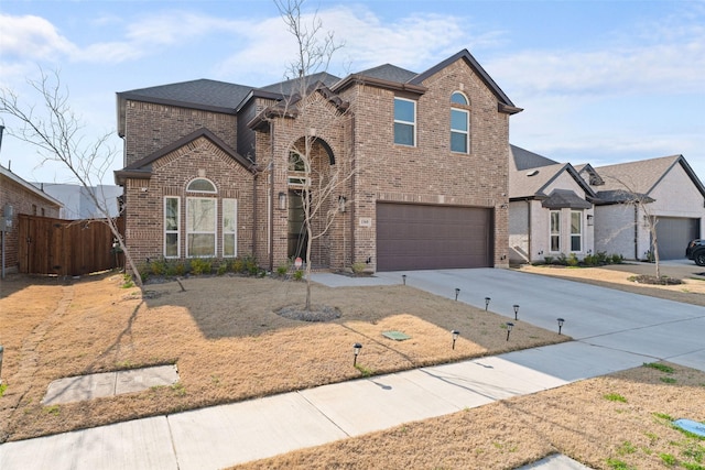 traditional-style house featuring driveway, brick siding, fence, an attached garage, and a shingled roof