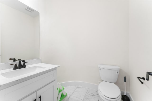 bathroom with vanity, toilet, baseboards, and marble finish floor