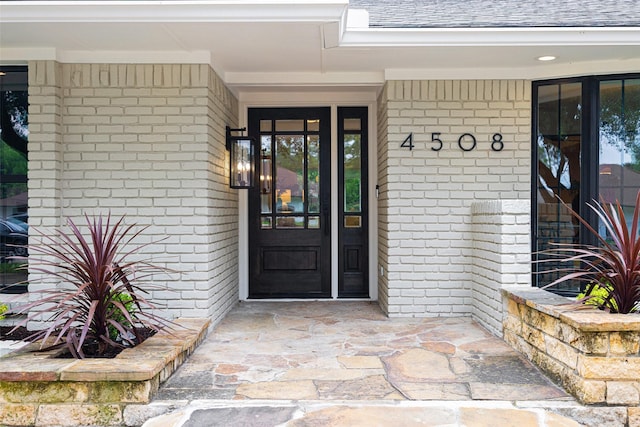 4508 Thunder Rd, Dallas, TX 75244 - doorway to property featuring brick siding, a shingled roof, and covered porch