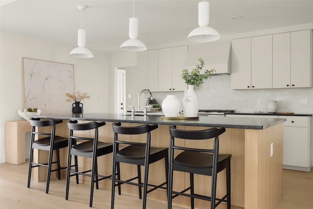 4508 Thunder Rd, Dallas, TX 75244 - kitchen with a sink, dark countertops, an island with sink, white cabinetry, and light wood-style floors